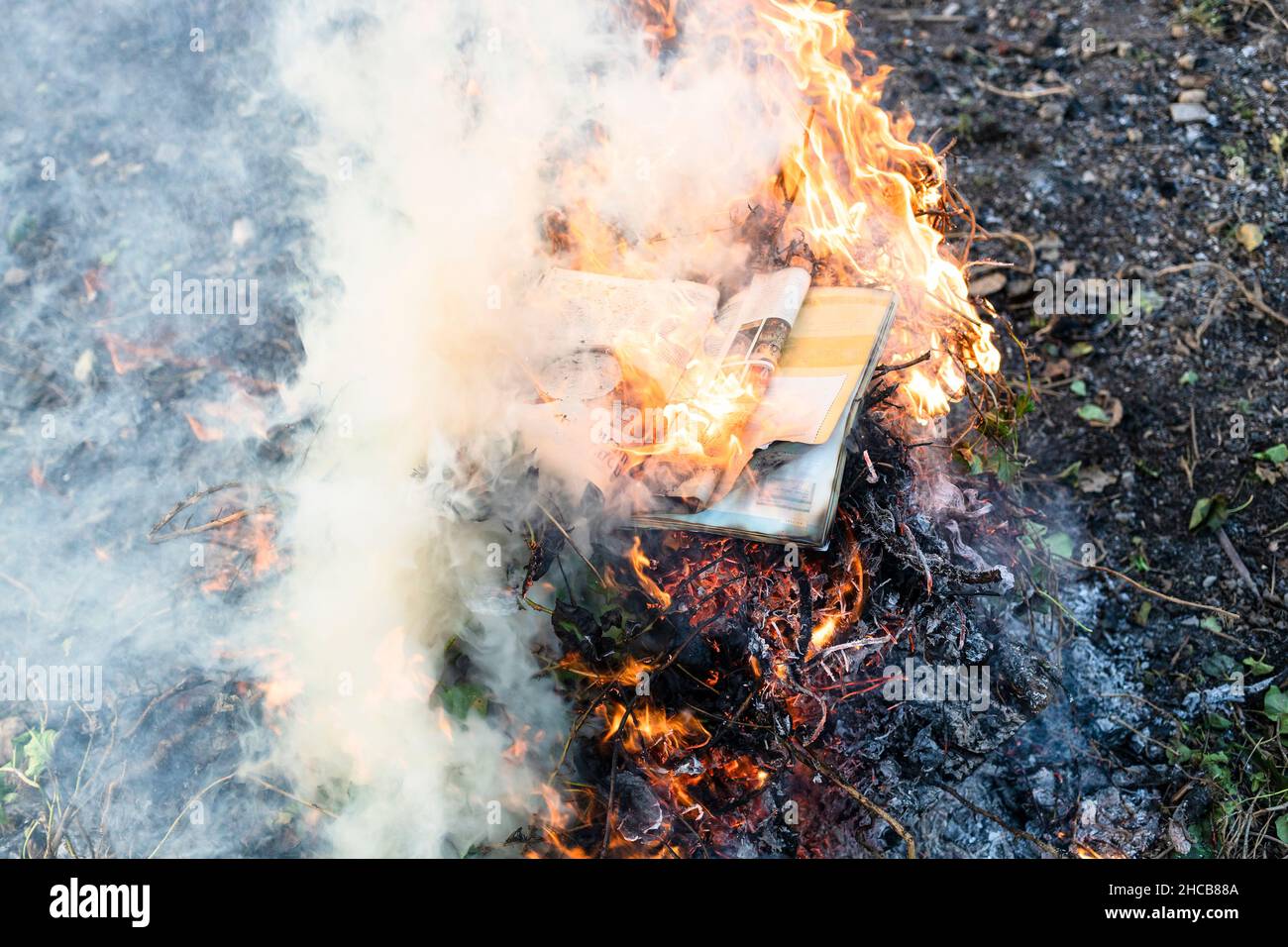 magazine brûlant dans le feu sur pile de plantes séchées dans le jardin de campagne Banque D'Images