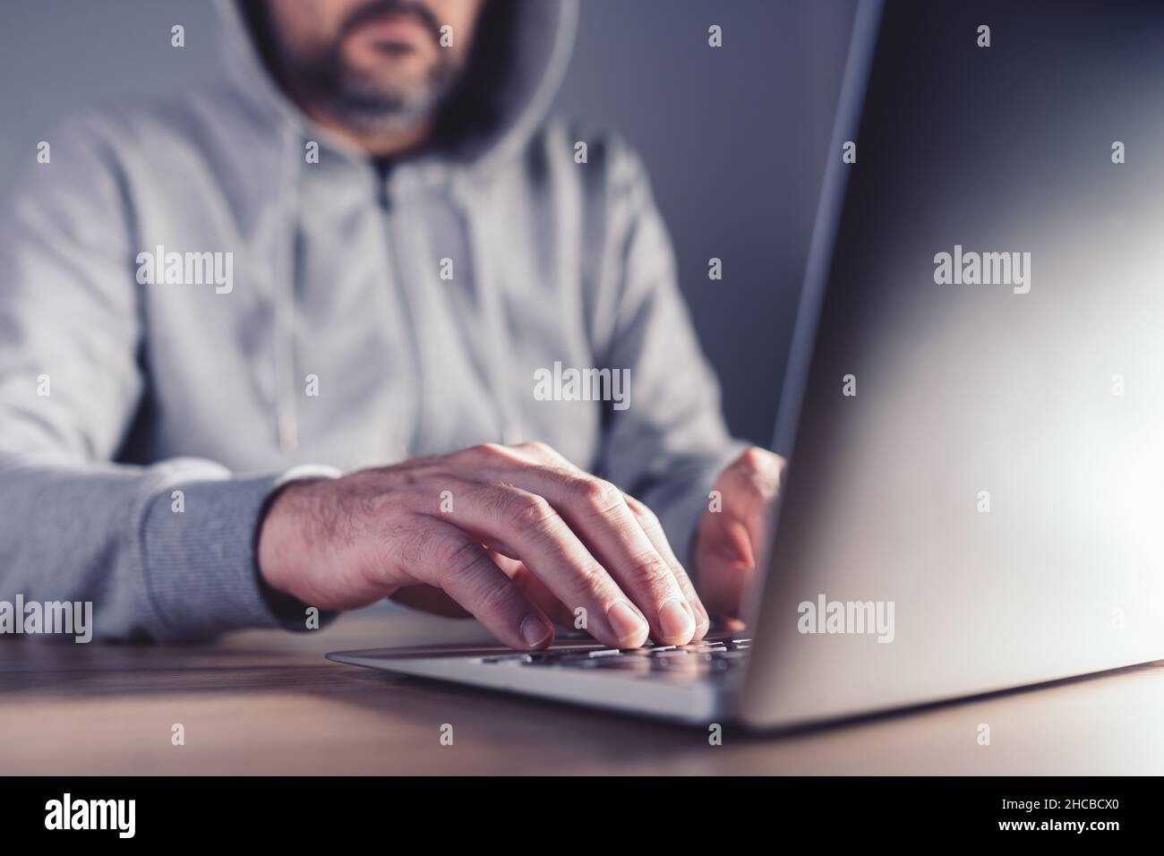 Concept de hacker chapeau gris, homme travaillant sur ordinateur portable pour découvrir les faiblesses du réseau informatique, focalisation sélective Banque D'Images