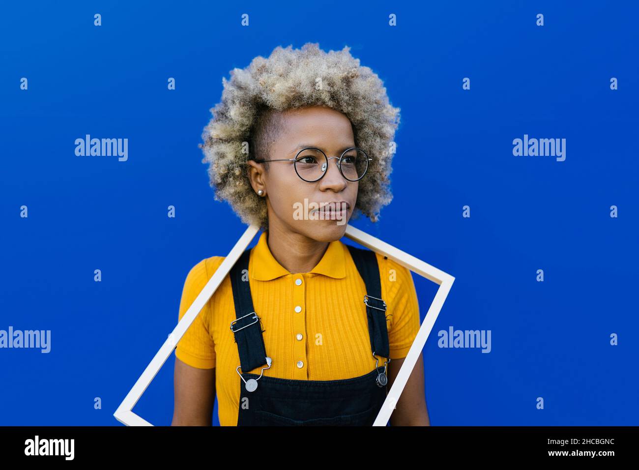 Femme avec cadre autour du cou devant le mur bleu Banque D'Images