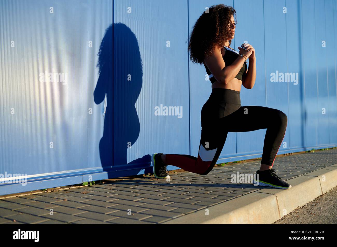 Sportswoman avec la main clasped squatting sur la piste de pied Banque D'Images