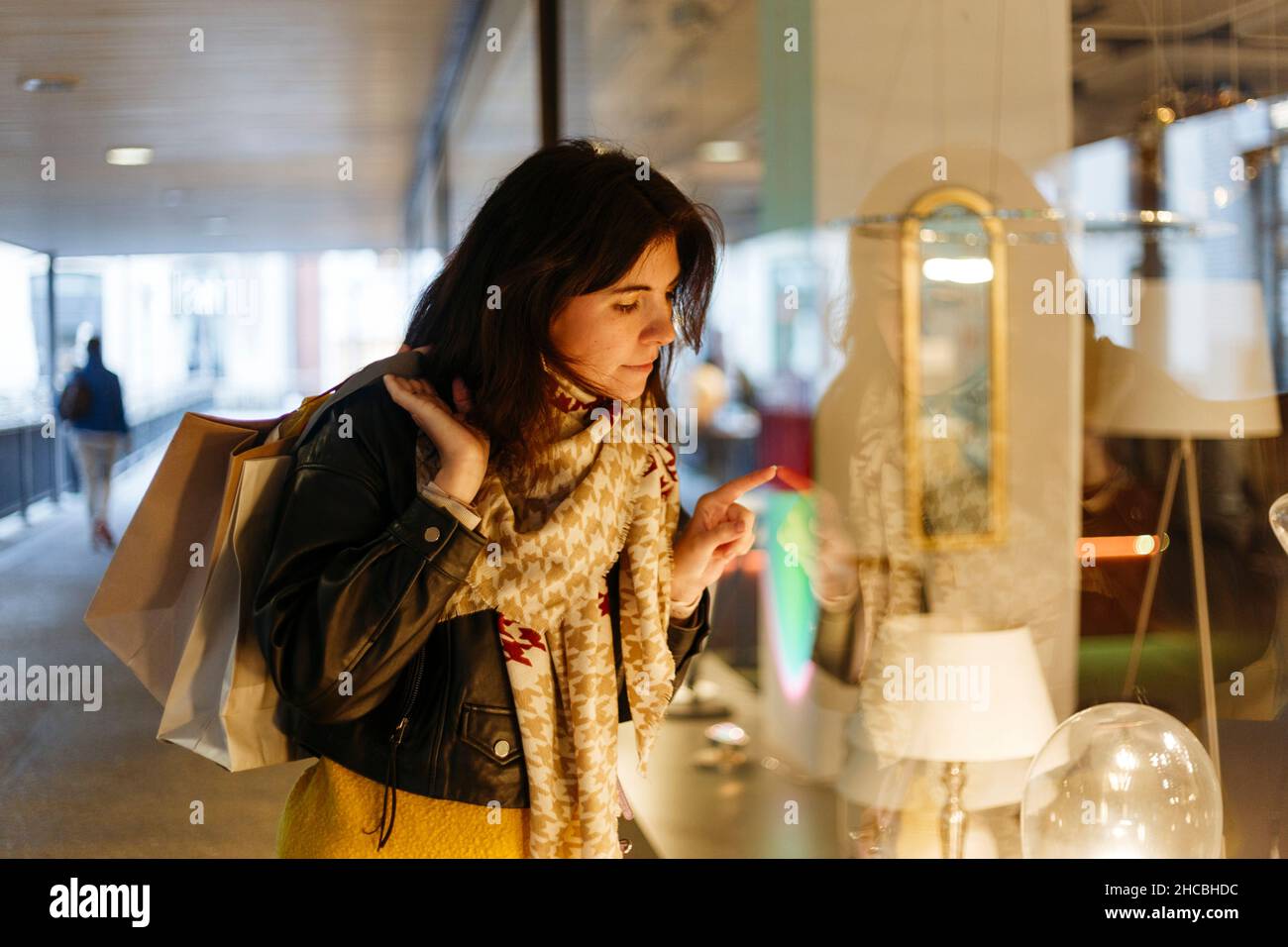 Femme utilisant un téléphone portable derrière la fenêtre du magasin Banque D'Images