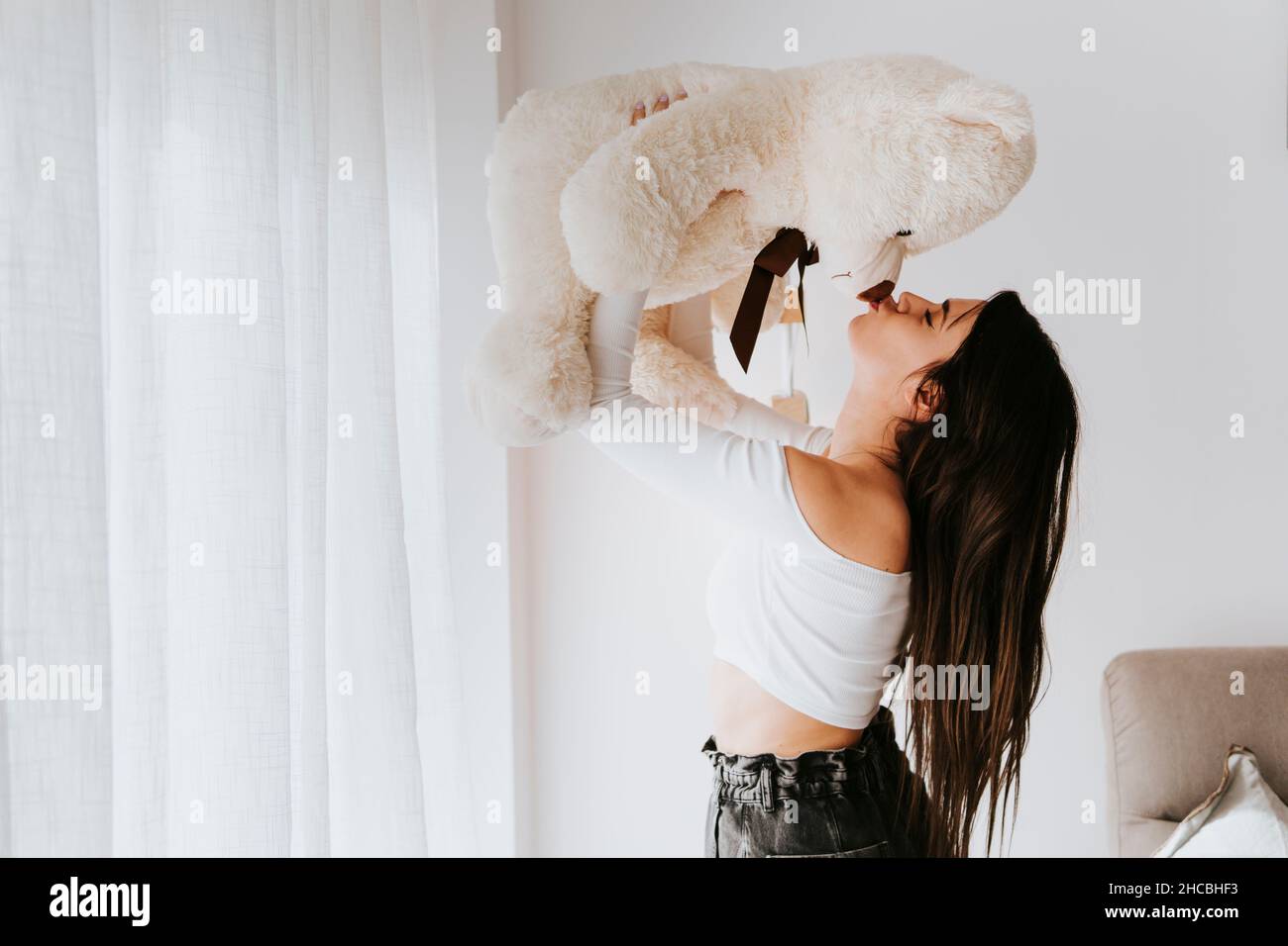 Femme embrassant un ours en peluche dans la salle de séjour Banque D'Images