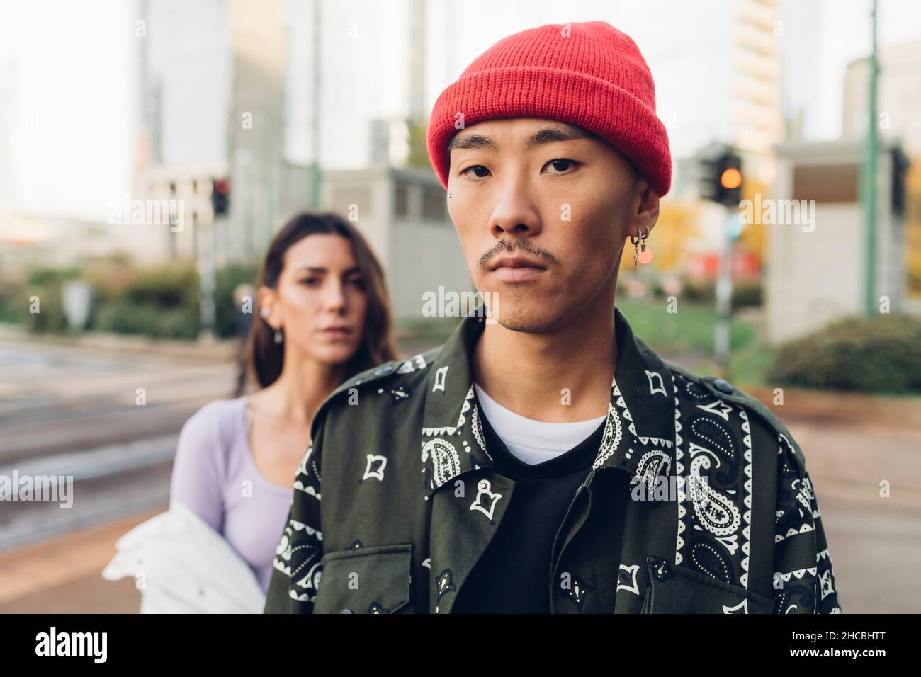Jeune homme portant un chapeau tricoté rouge avec une femme en arrière-plan Banque D'Images