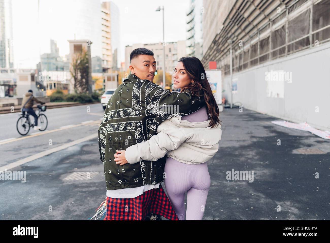 Un jeune couple regarde les épaules en marchant sur le trottoir de la ville Banque D'Images