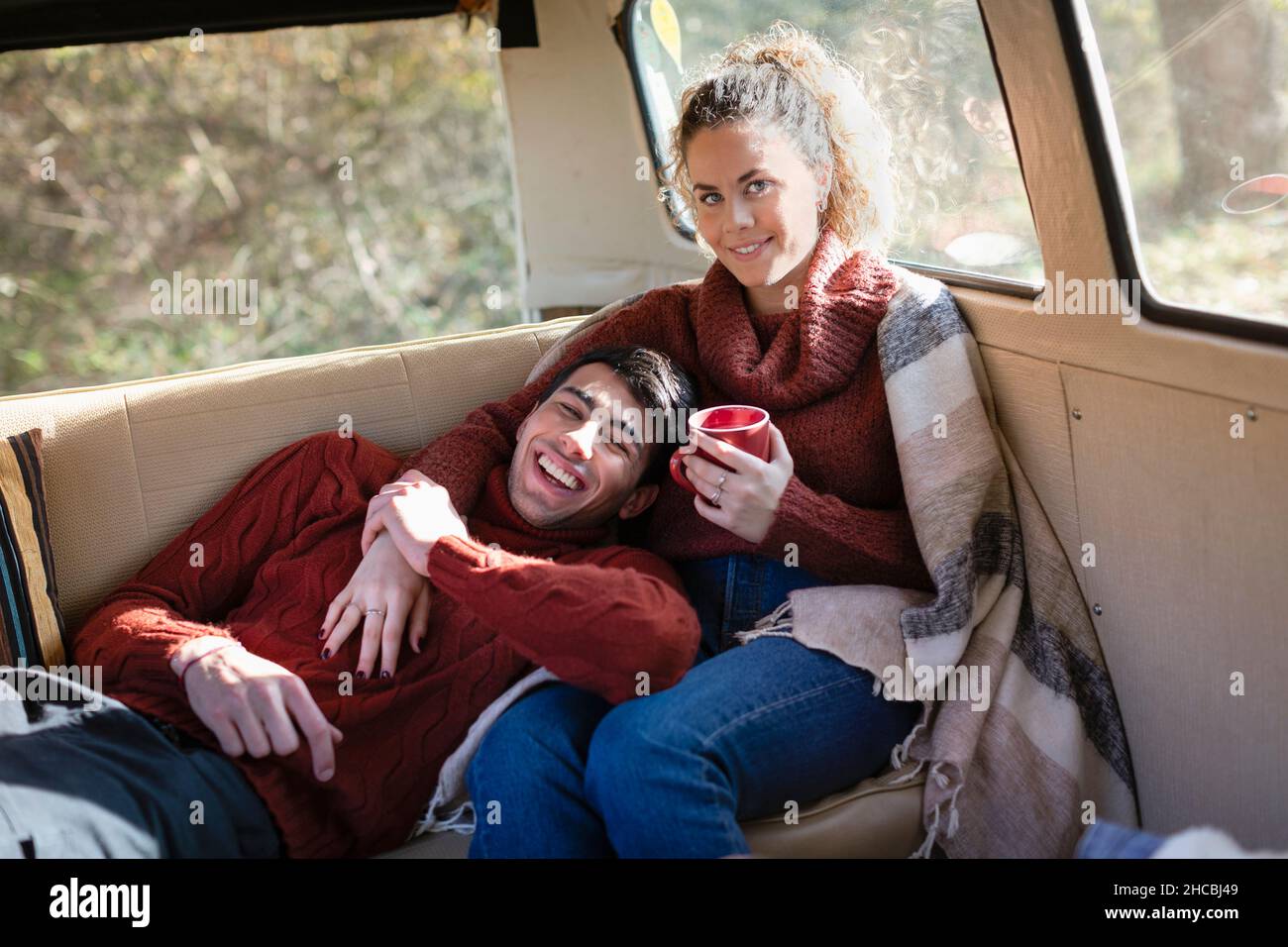 Un homme heureux allongé sur les genoux de sa petite amie en minibus le week-end Banque D'Images