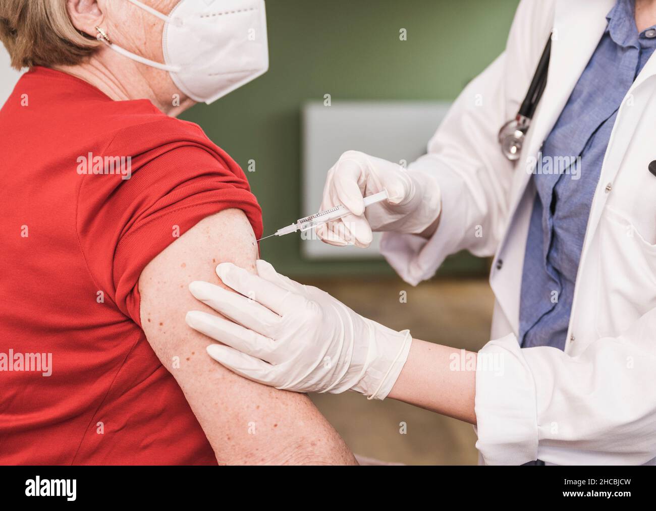 Médecin vaccinant une femme portant un masque facial à la maison Banque D'Images