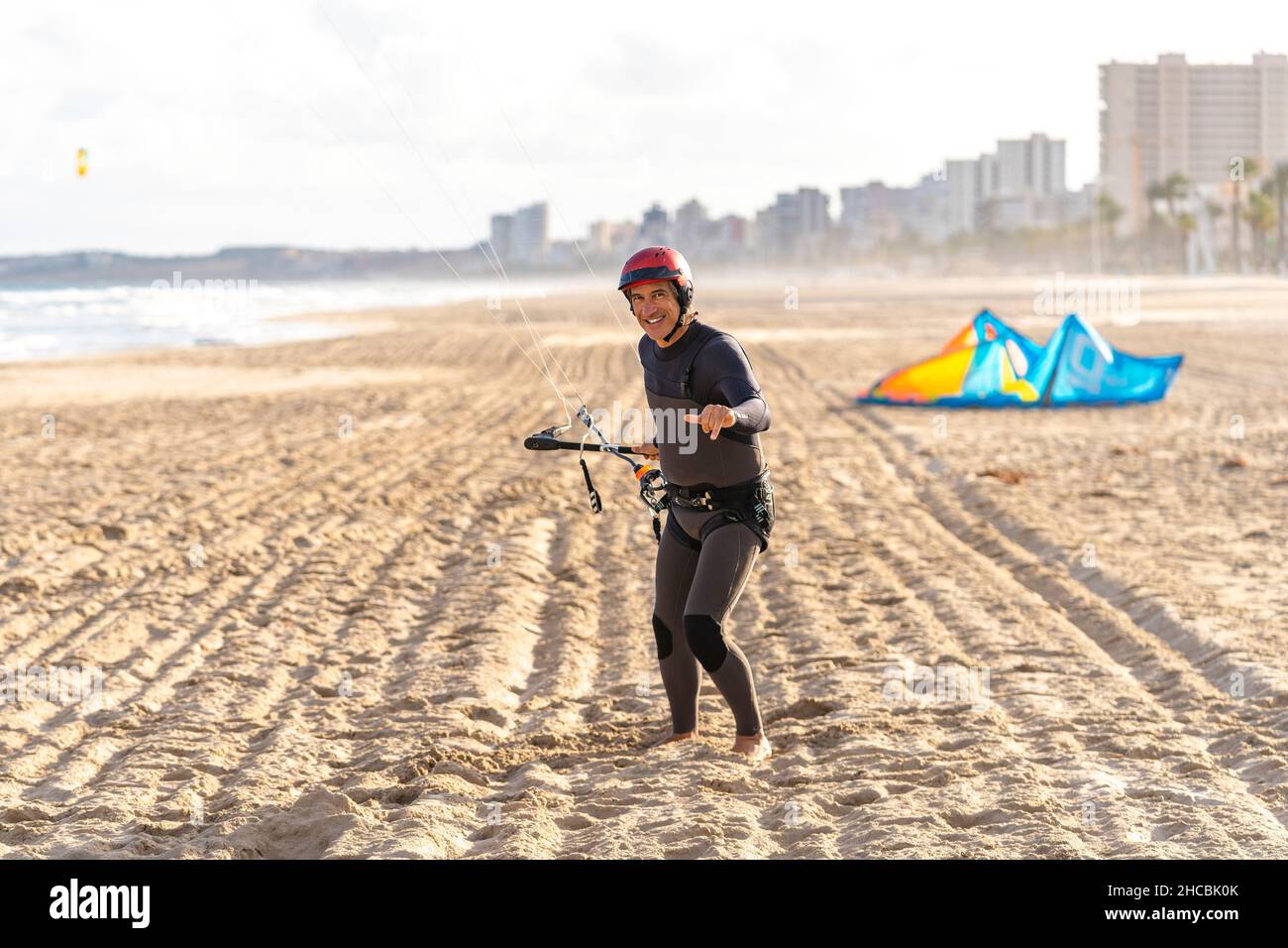 Homme souriant portant un casque de sport debout sur le sable Banque D'Images
