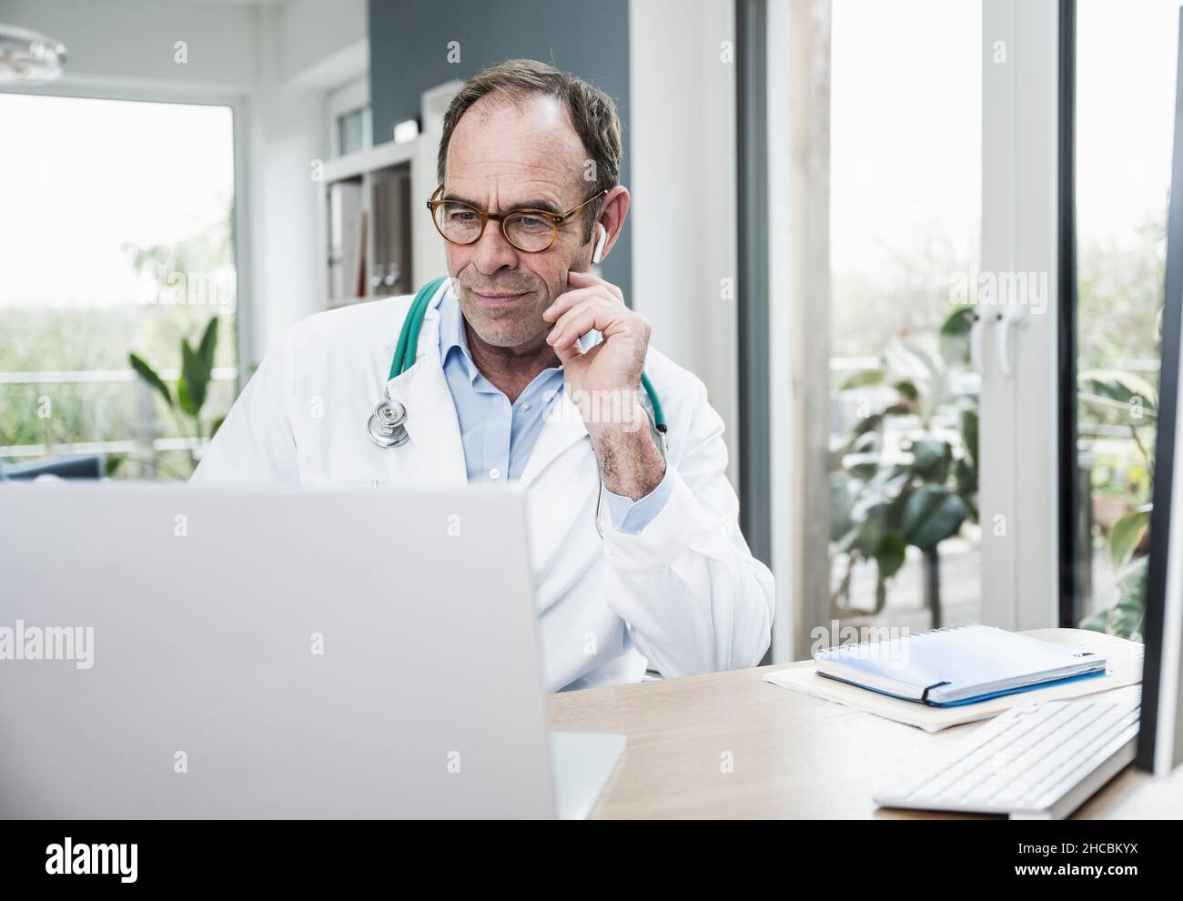 Médecin utilisant un ordinateur portable se concentrant sur un bureau en clinique Banque D'Images