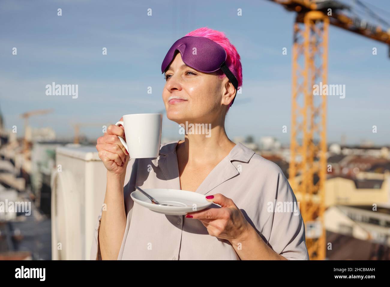 Femme avec masque oculaire buvant du café le jour ensoleillé Banque D'Images