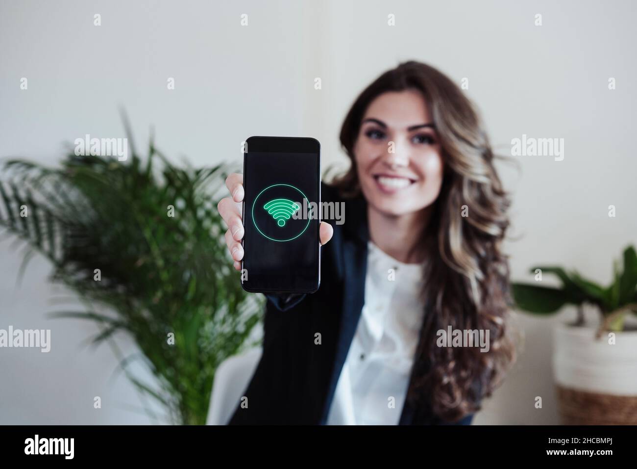 Femme d'affaires montrant un smartphone avec logo wifi Banque D'Images