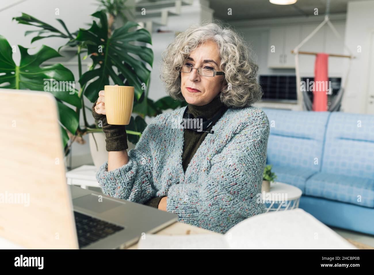 Femme âgée tricoter et coudre dans la salle de séjour Banque D'Images