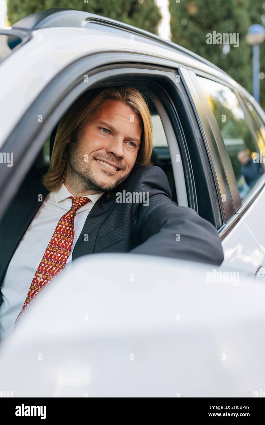 Homme d'affaires souriant regardant par la fenêtre de la voiture Banque D'Images