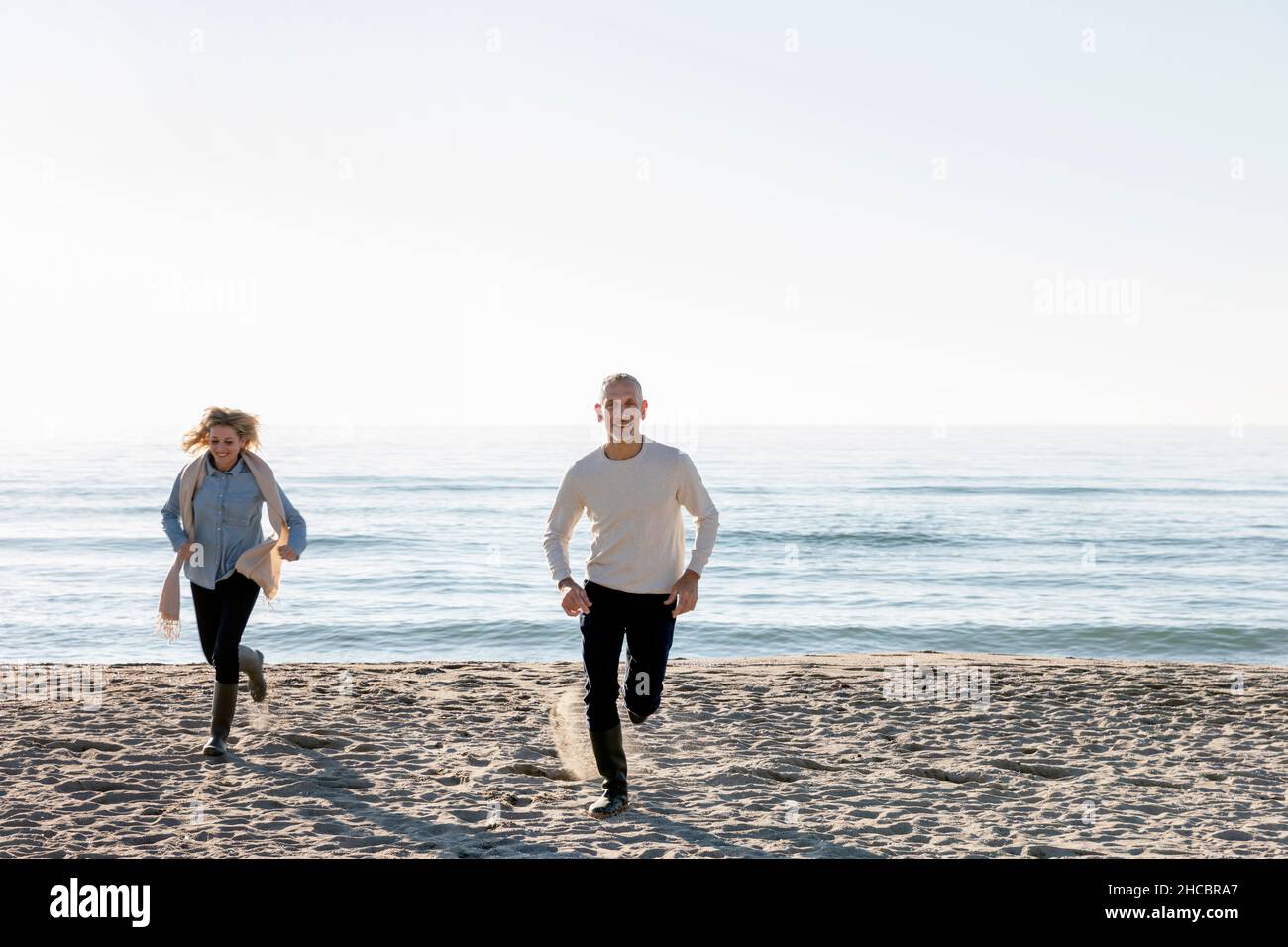Homme et femme en train de courir sur le sable à la plage Banque D'Images