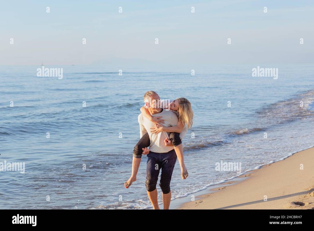 Man piggybacking woman at beach Banque D'Images