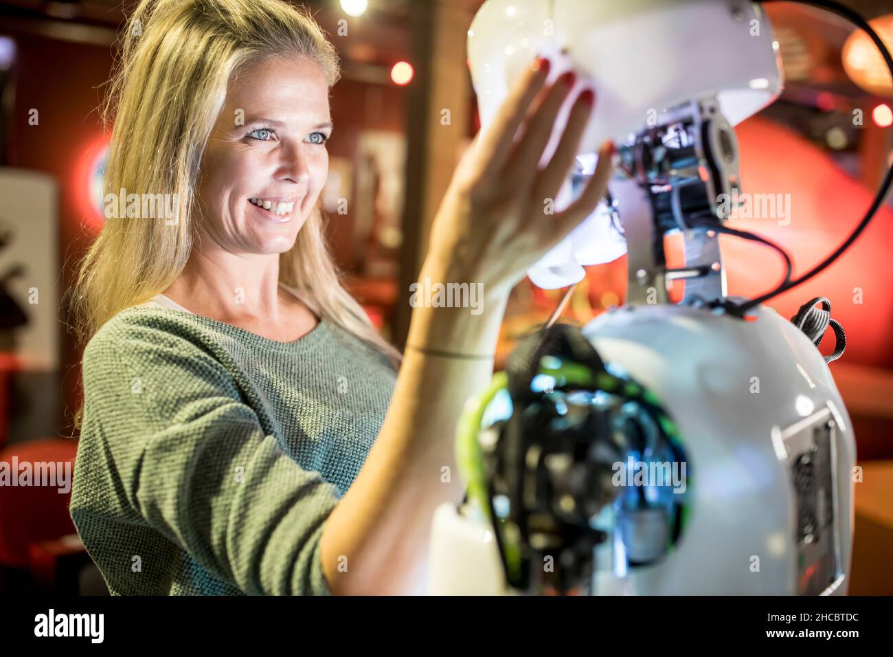 Un technicien satisfait qui regarde le robot humain en atelier Banque D'Images