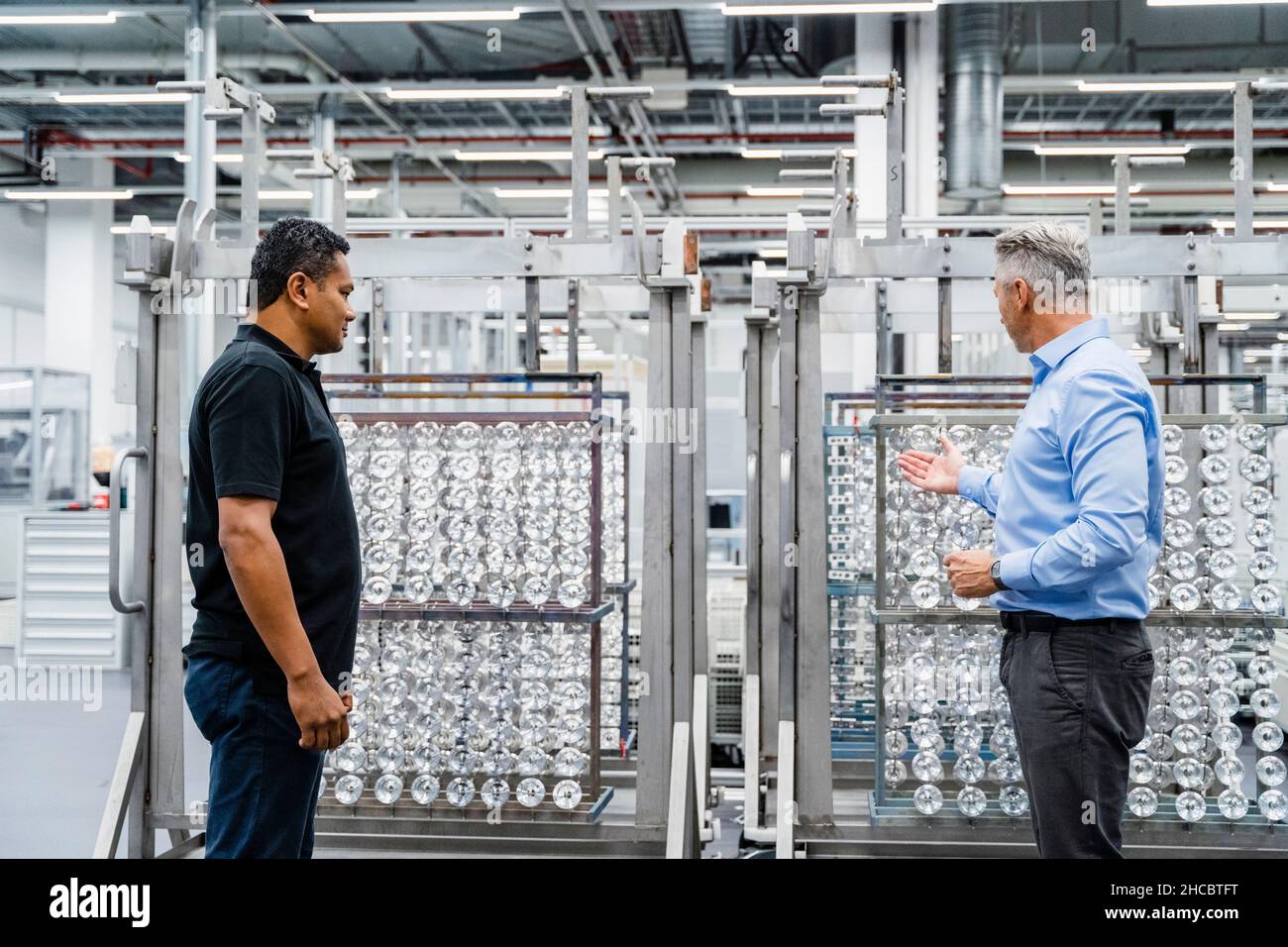 Homme d'affaires discutant avec l'ingénieur de maintenance de l'équipement industriel Banque D'Images