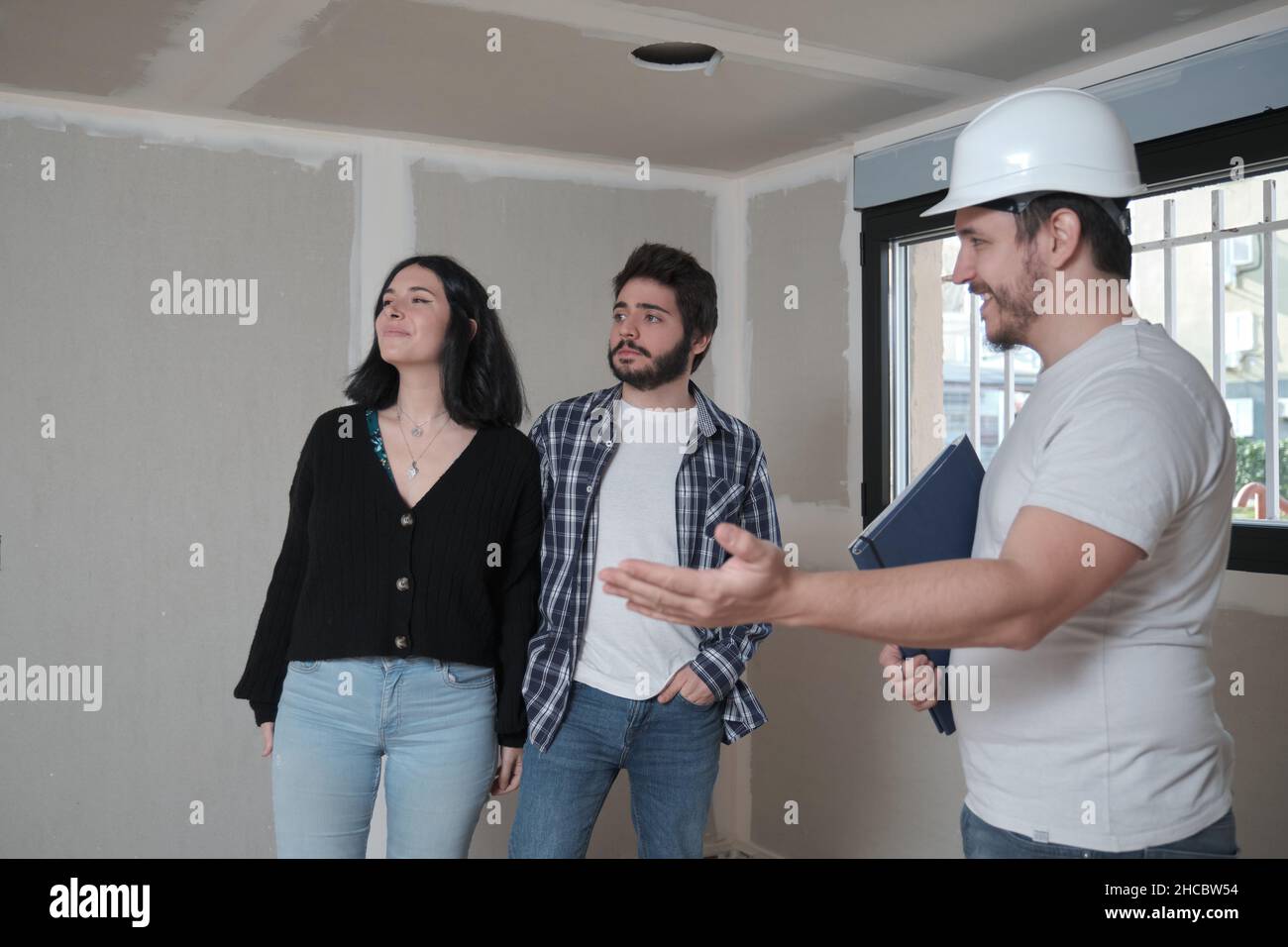 L'architecte montre un nouvel appartement en construction à un jeune couple intéressé à acheter. Banque D'Images