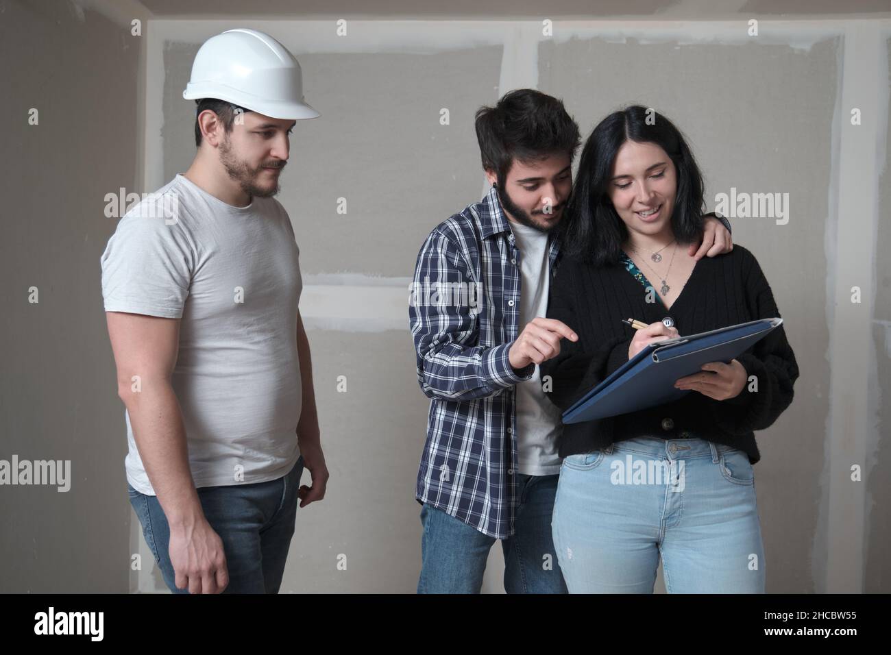 Femme d'un jeune couple signant un document pour acheter la maison en construction. Banque D'Images