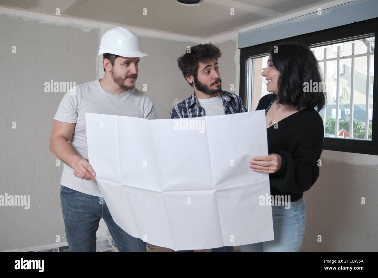L'architecte montre l'appartement dans des plans de construction à un jeune couple intéressé. Banque D'Images