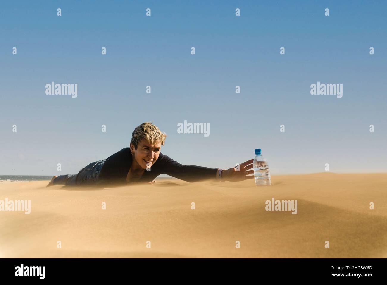 Une femme qui cherche désespérément une bouteille d'eau sur le désert de sable Banque D'Images
