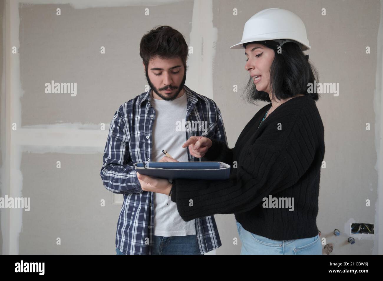 Un jeune homme signe un document pour acheter une maison dans la construction. Banque D'Images