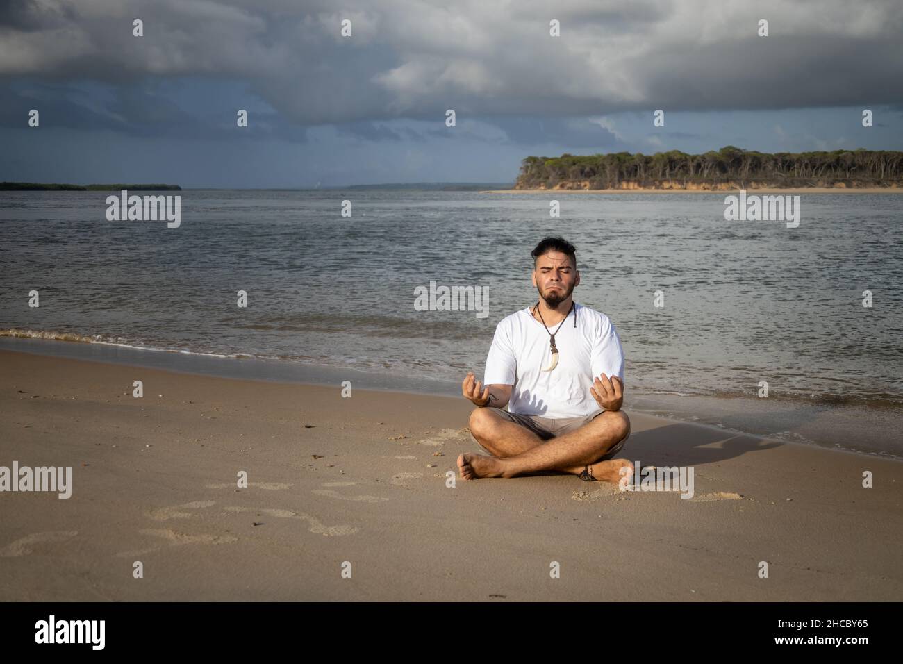 Homme blanc entre 25 et 30 ans au bord de la mer faisant du yoga.Méditation dans la nature. Banque D'Images