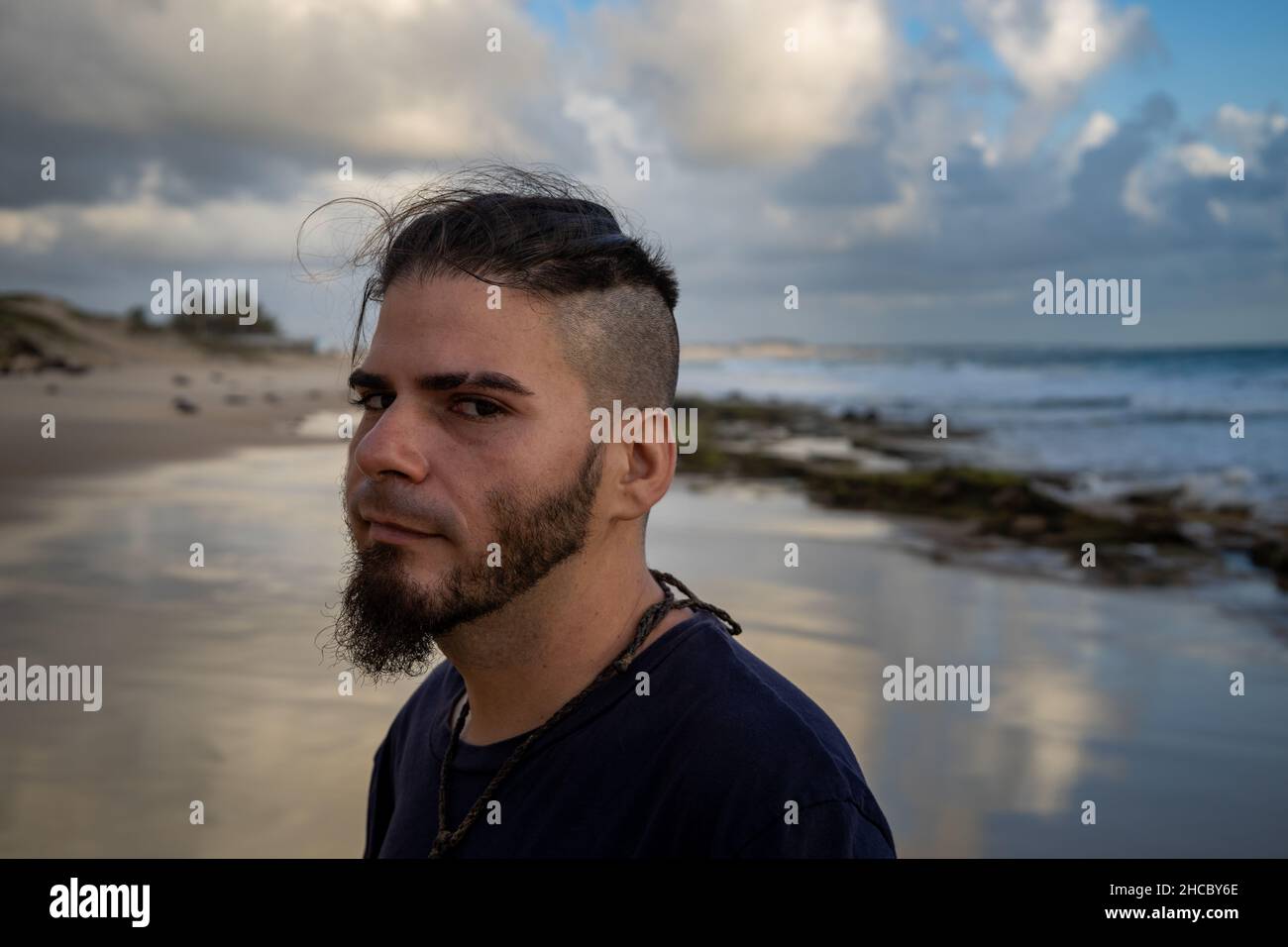 Homme blanc entre 25 et 30 ans avec une coupe de cheveux moderne et une attitude suspecte au bord de la mer. Banque D'Images