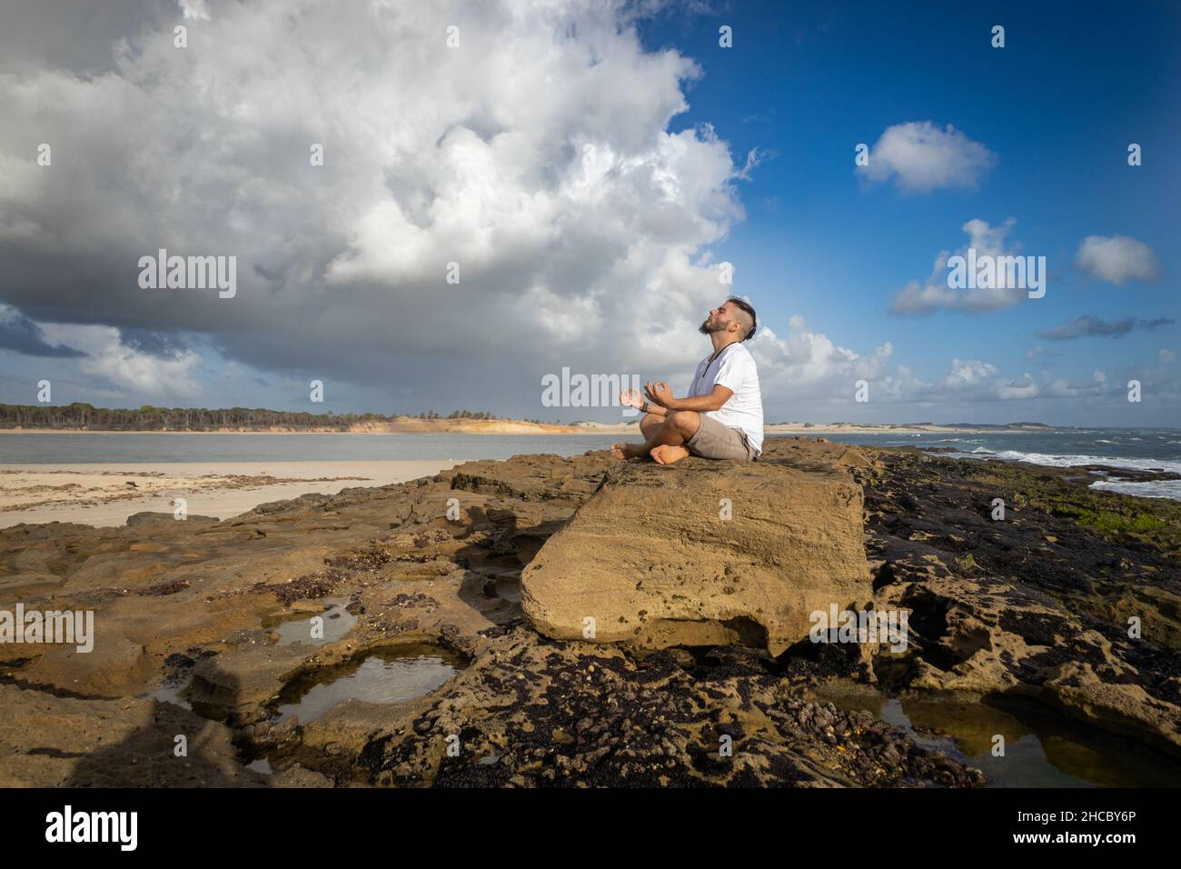 Homme blanc entre 25 et 30 ans au bord de la mer faisant du yoga.Méditation dans la nature. Banque D'Images