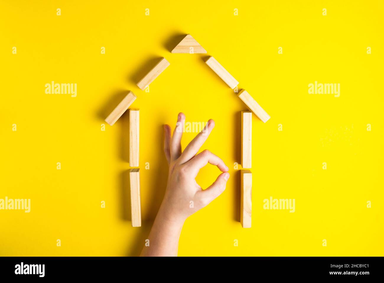 Vue de dessus de la main de l'enfant gros plan des blocs de construction montrant ok, maison, cabane en bois Banque D'Images