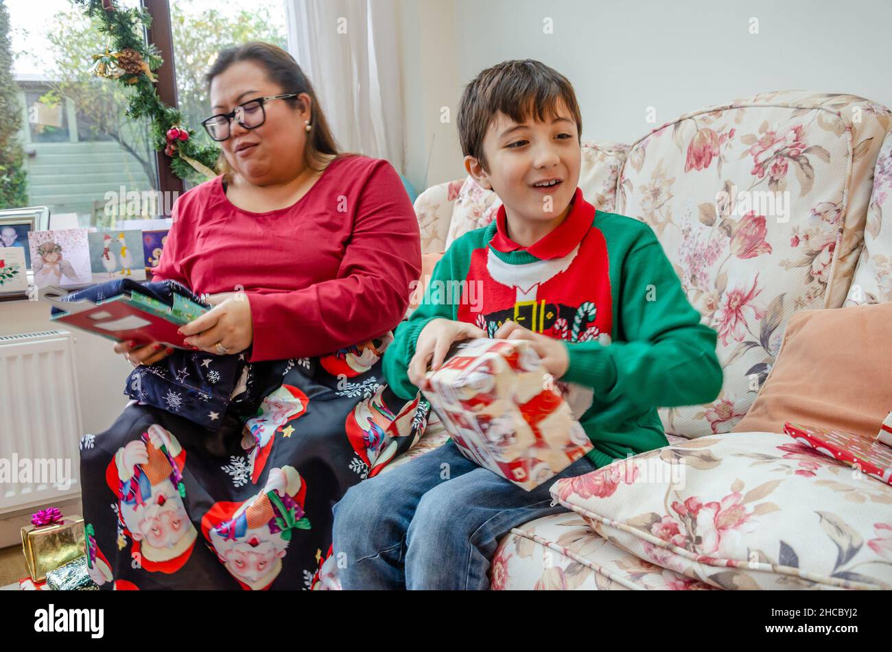 Mère et son fils se sont assis ensemble sur un cadeau d'ouverture de seettee le jour de Noël Banque D'Images