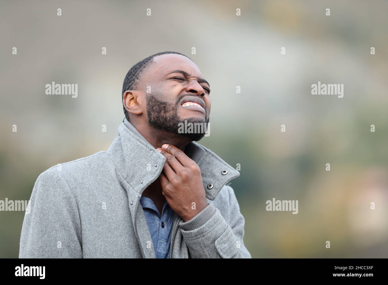 Homme malade avec peau noire souffrant mal de gorge en plein air en hiver Banque D'Images