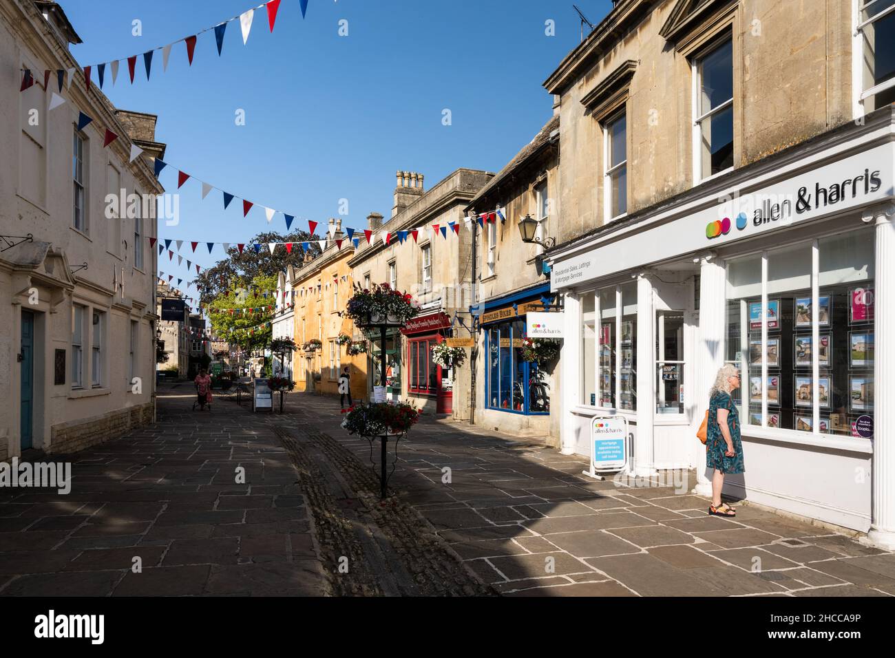 Les boutiques sont décorées de banderoles et de paniers de fleurs sur la traditionnelle High Street de Corsham dans le Wiltshire. Banque D'Images