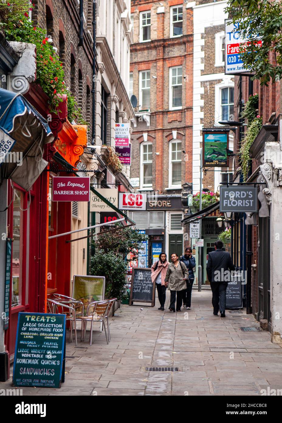 Des piétons marchent devant les boutiques et les cafés de Red Lion Square dans le centre de Londres. Banque D'Images