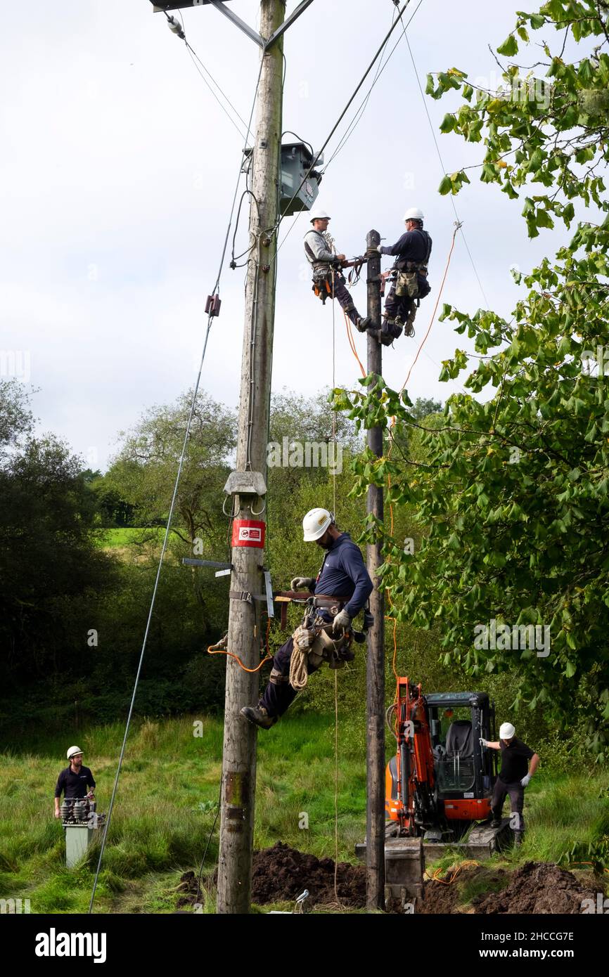 Travailleurs de l'électricité remplaçant l'ancien poteau de service public et rebranchant les câbles d'équipement électrique sur la propriété rurale au pays de Galles Grande-Bretagne KATHY DEWITT Banque D'Images