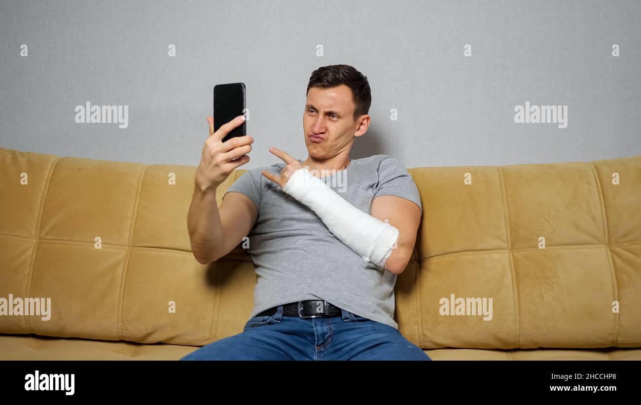 Un jeune homme fait des selfies montrant des avant-bras cassés et posant Banque D'Images