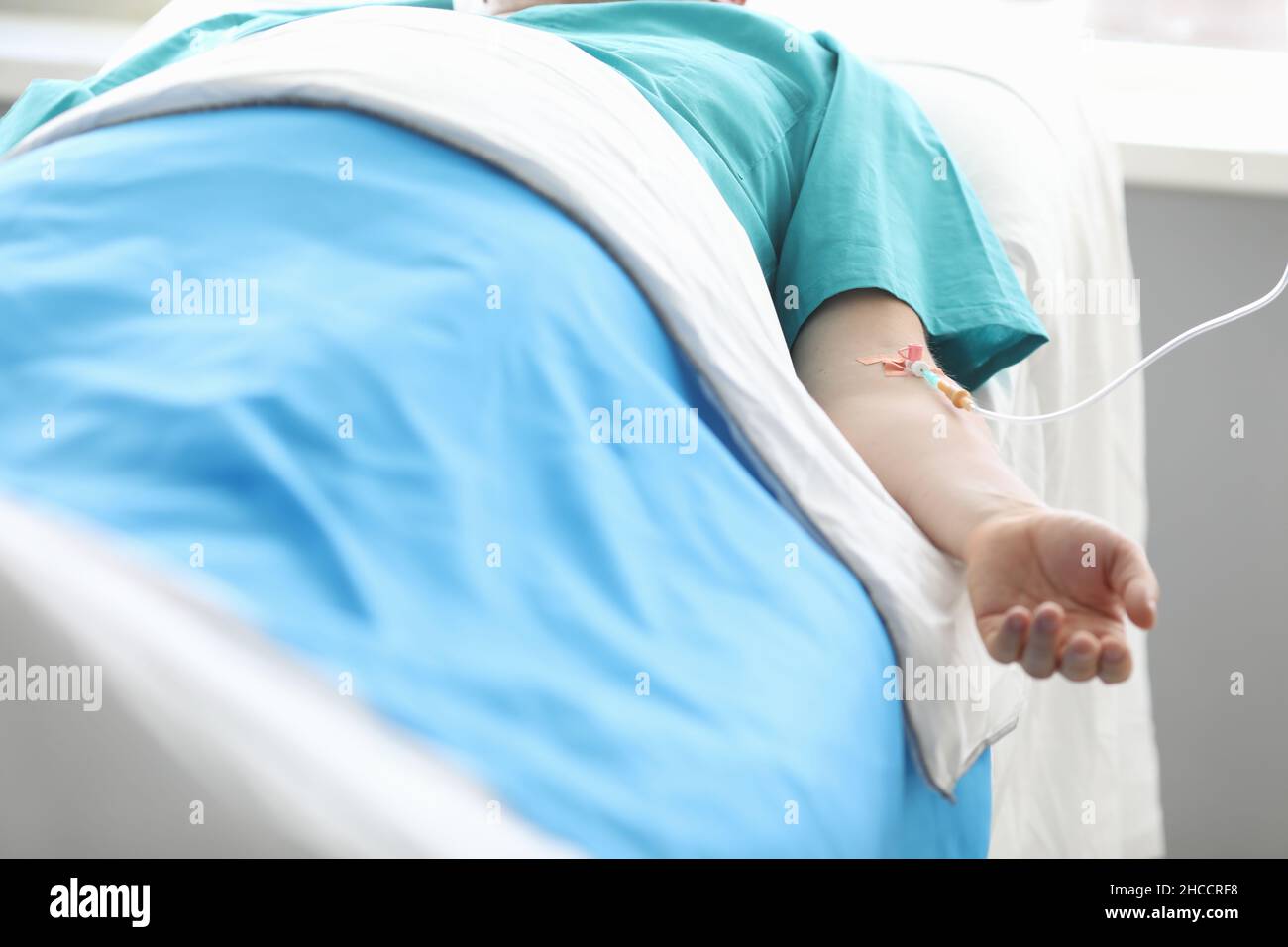 Patient mâle allongé sur le lit avec perfusion intraveineuse dans sa main rapprochée Banque D'Images