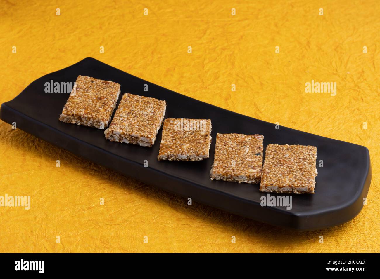 Bonbons traditionnels Mitthai de l'Inde isolé sur fond jaune pour Makar Sankranti Lohri Gajak également connu sous le nom de Gur Gajjak Gazak Gachak til Patti Banque D'Images