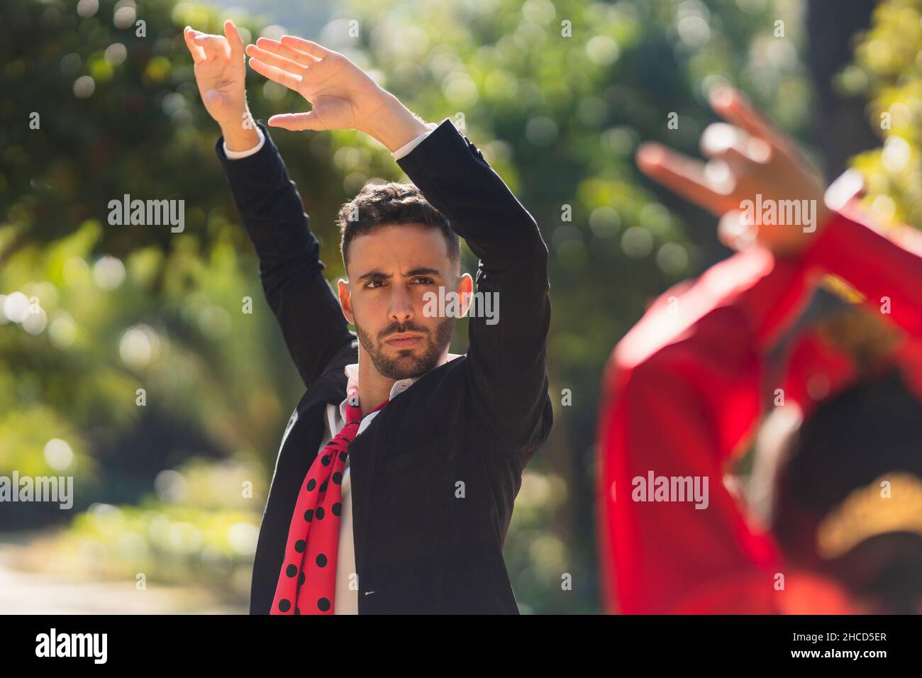 Homme levant les bras tout en dansant le flamenco avec une femme en robe flamenco Banque D'Images