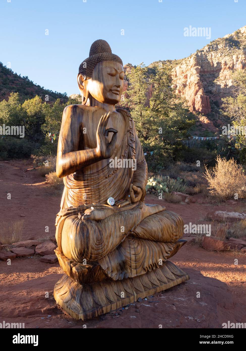 Statue de Bouddha Shakyamuna en bois sculpté avec falaises de grès rouges en arrière-plan.Photographié à l'Amitubha Stupa and Peace Park à Sedona, Arizona. Banque D'Images