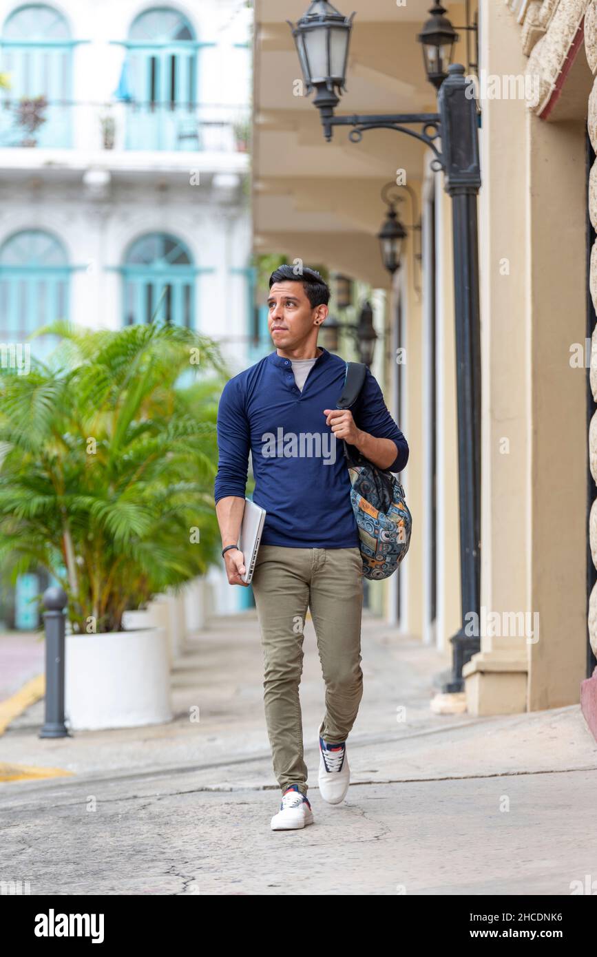 Jeune latino homme marchant dans la rue avec son ordinateur portable, Panama ville, Amérique centrale Banque D'Images