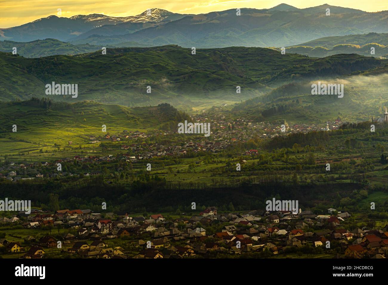 Maramures avec des maisons de la ville d'Ieud et les montagnes carpathes derrière, pendant un lever de soleil brumeux.Photo prise le 16th mai 2021 près de moi Banque D'Images