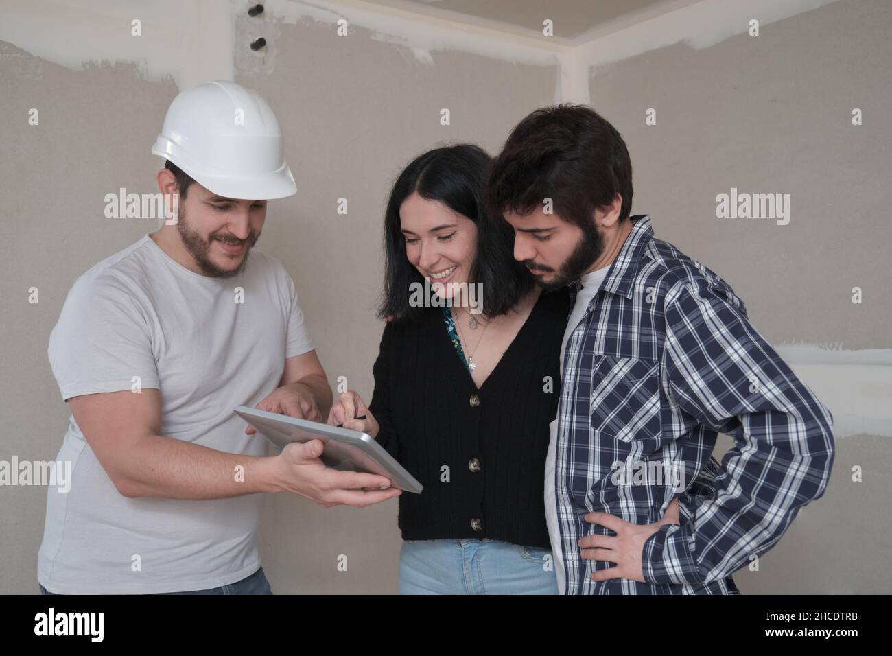 Femme d'un jeune couple signant un document pour acheter maison dans une tablette. Banque D'Images