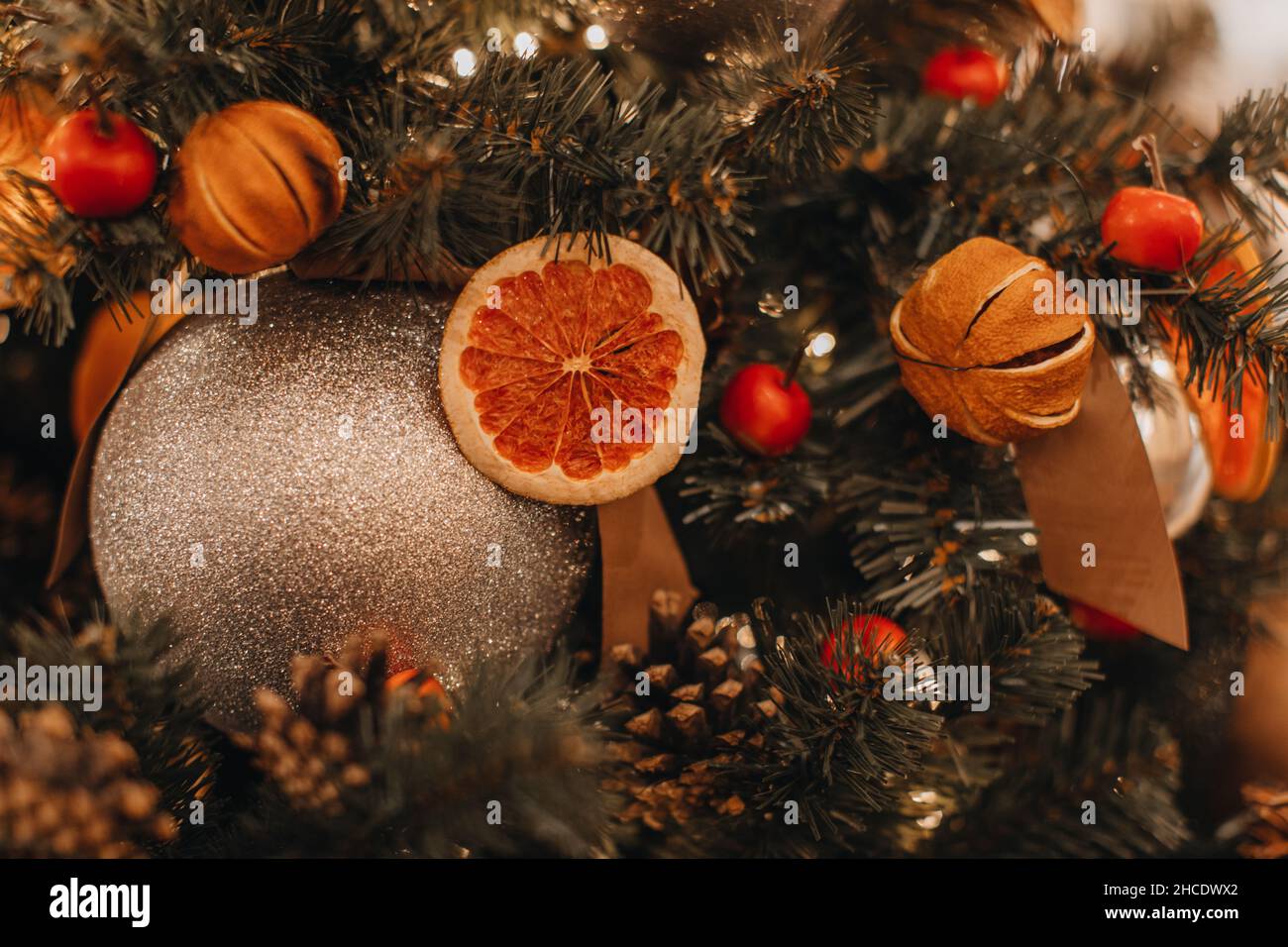 Oranges séchées, baies, cônes accrochés à l'arbre de Noël.Détails festifs créatifs et boule de Noël dorée.Décor hivernal magique du nouvel an Banque D'Images