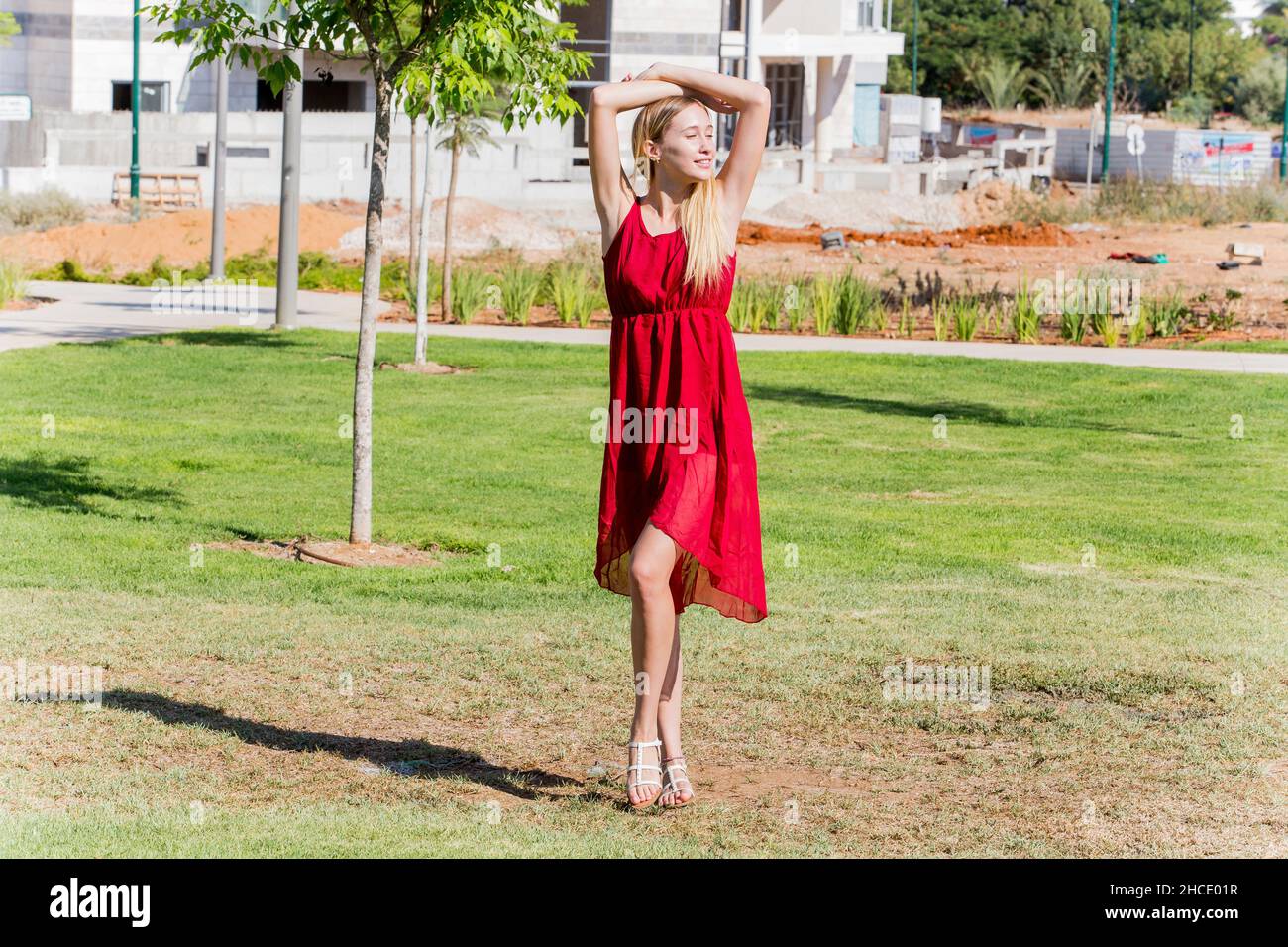 La jeune femme en robe rouge apprécie l'air frais dehors Banque D'Images