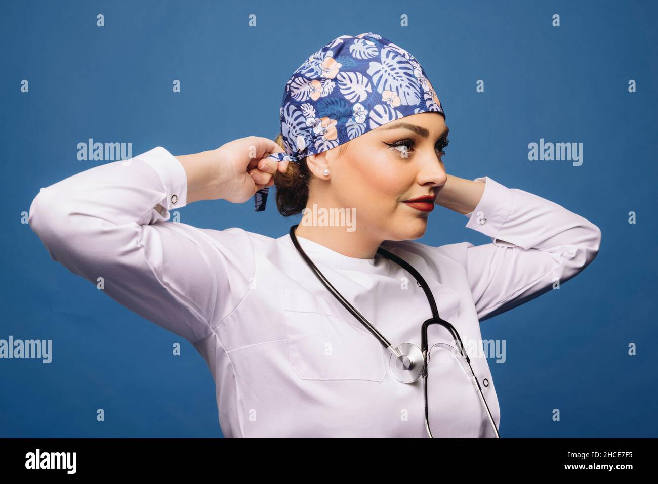 Médecin femme portant une robe blanche médicale et stéthoscope nouant un bandana uniforme sur la tête Banque D'Images