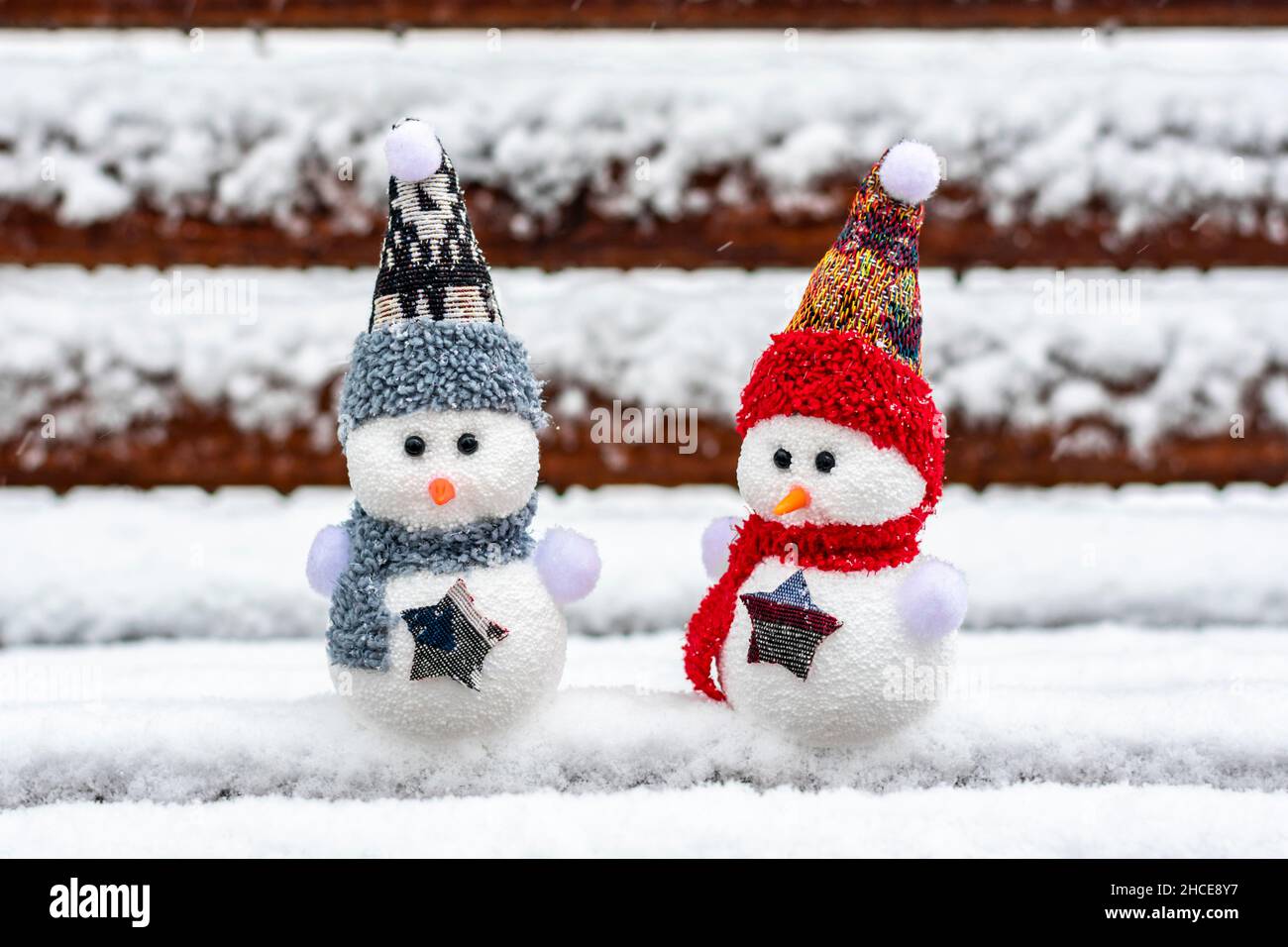 Joyeux noël et bonne année carte de voeux avec espace copie deux petits bonshommes de neige heureux en rouge, bleu casquette et écharpe debout dans le fond de neige d'hiver Banque D'Images