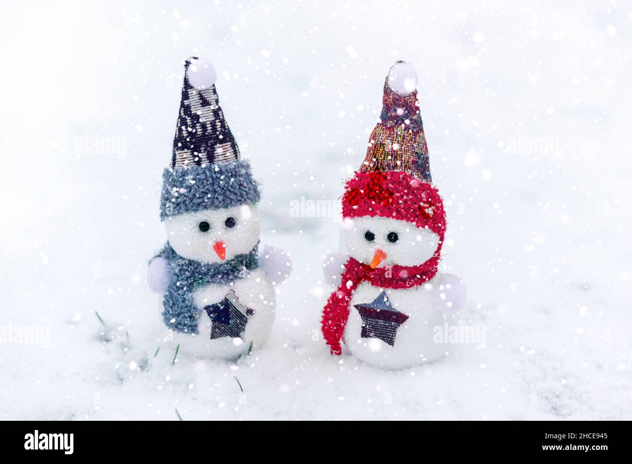 Joyeux noël et bonne année carte de voeux avec espace copie deux petits bonshommes de neige heureux en rouge, bleu casquette et écharpe debout dans le fond de neige d'hiver Banque D'Images