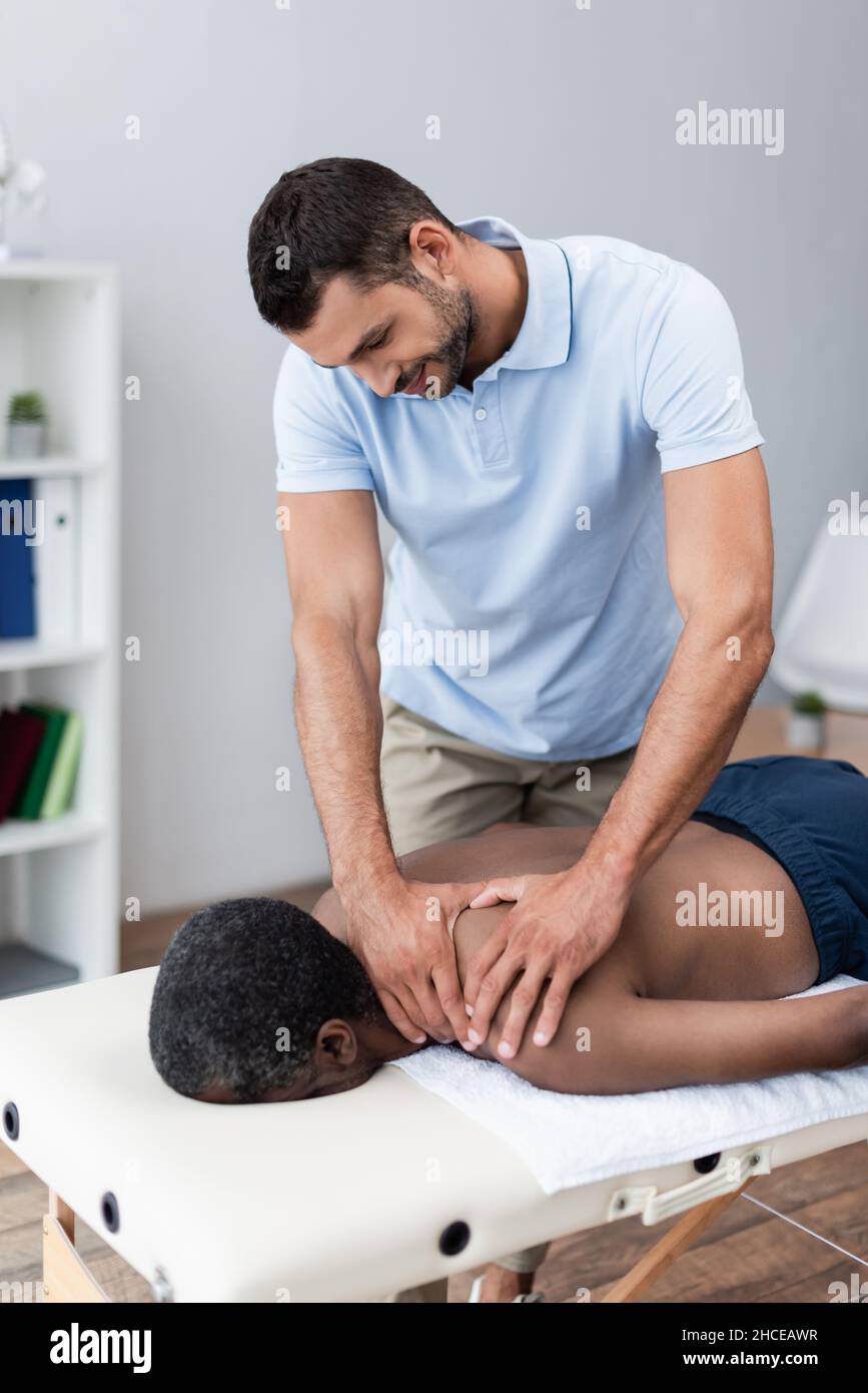 homme afro-américain recevant un massage d'épaule dans le centre de réadaptation Banque D'Images