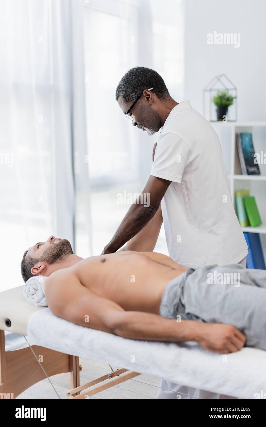 un physiothérapeute afro-américain massant un homme dans un centre de réadaptation Banque D'Images