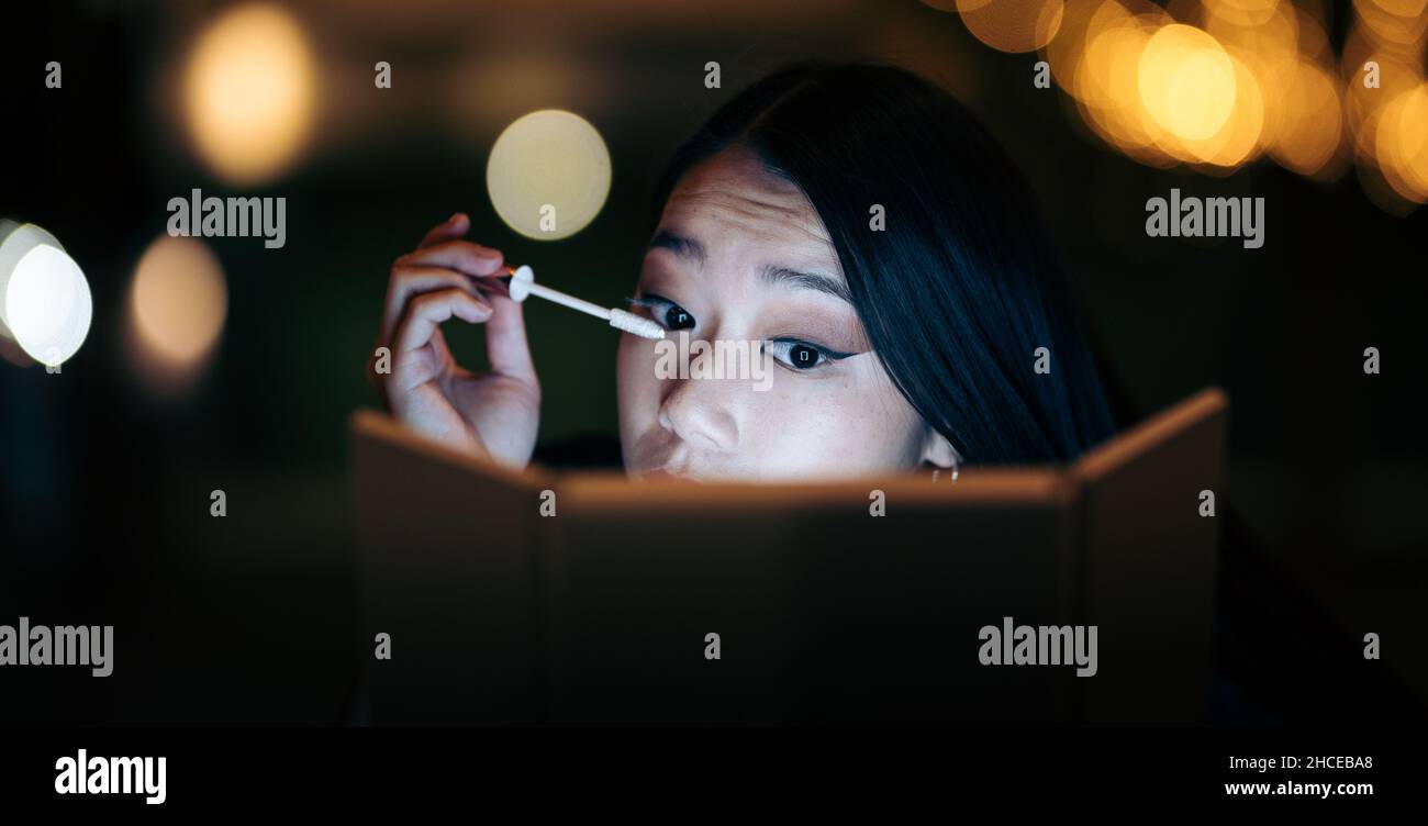 Une jeune femme asiatique se maquillant dans la rue Banque D'Images